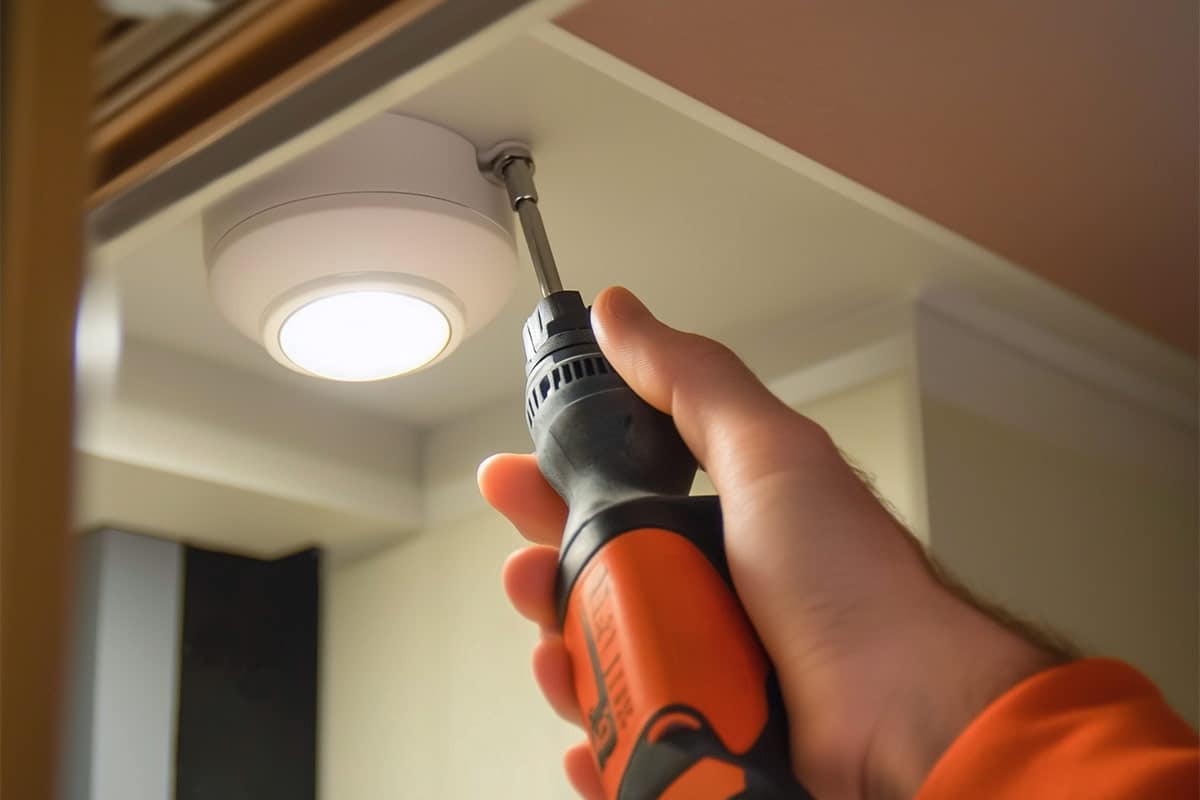 Installing countertop lights with powered screwdriver.