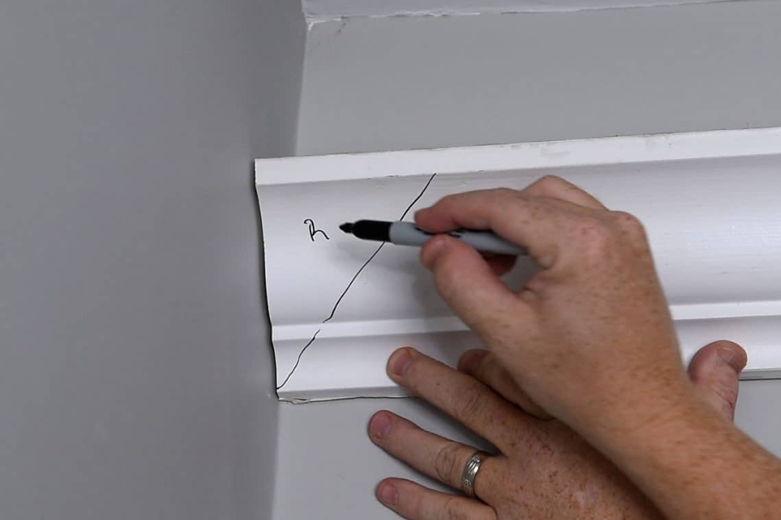 Closeup of one side of an inside crown molding corner being marked for cutting.