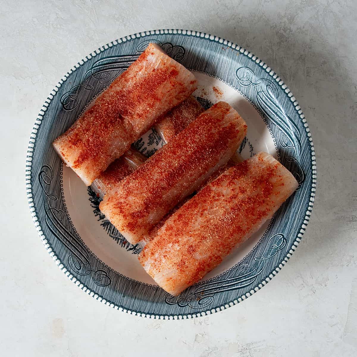 Seasoned mahi filets laid on a plate.