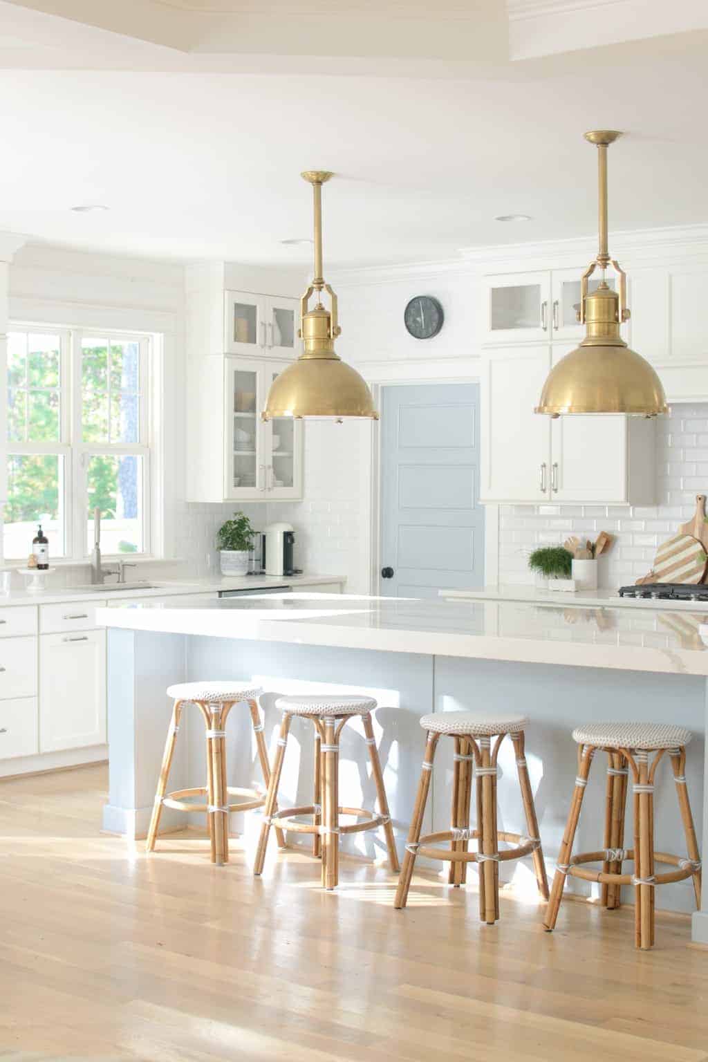 Coastal chic kitchen with brass accents and white backsplash. Island and door painted in Sherwin williams Krypton Blue.