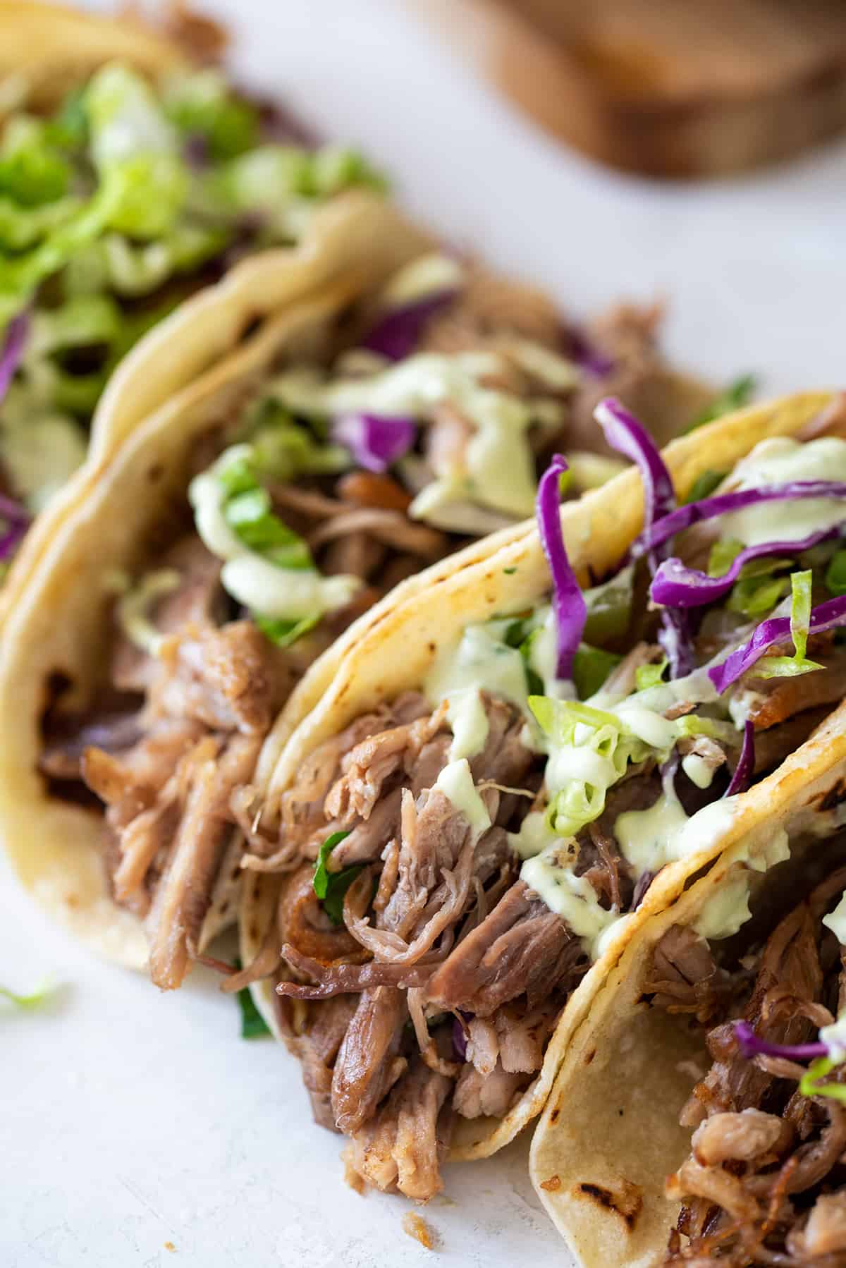 Carnitas filled tacos top with cabbage, sour cream, and cilantro.