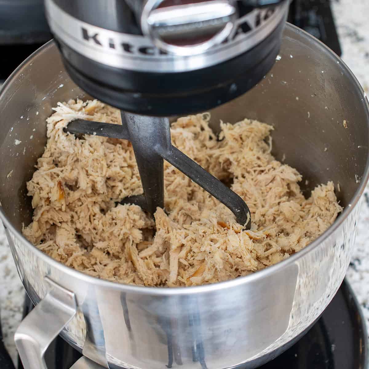 A KitchenAid stand mixer full of shredded chicken.