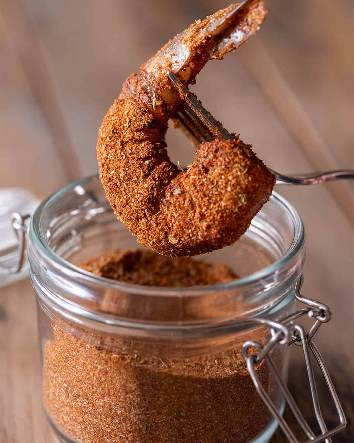 Closeup of a shrimp after being dipped into a jar of seasoning.
