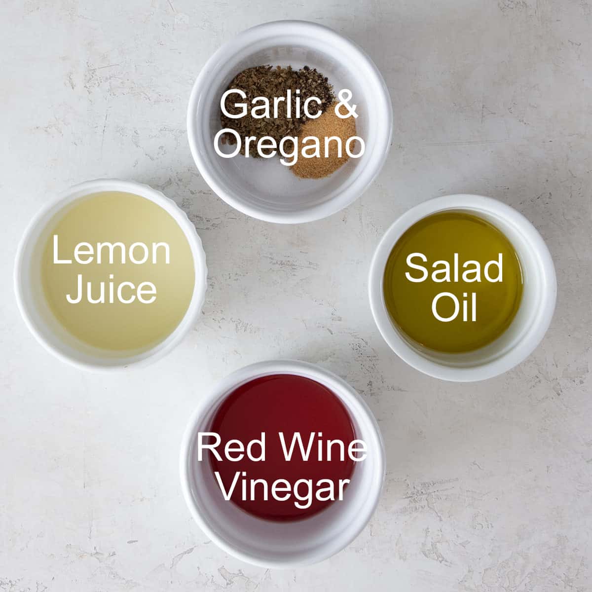 Ingredients for a simple Mediterranean vinaigrette dressing in cups with labels.