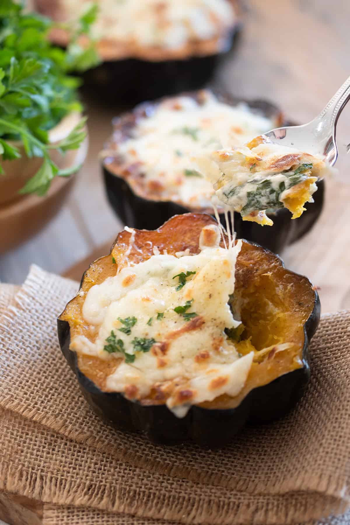 Spinach stuffed squash with a spoon scooping the filling out to show the melted cheese and spinach filling.