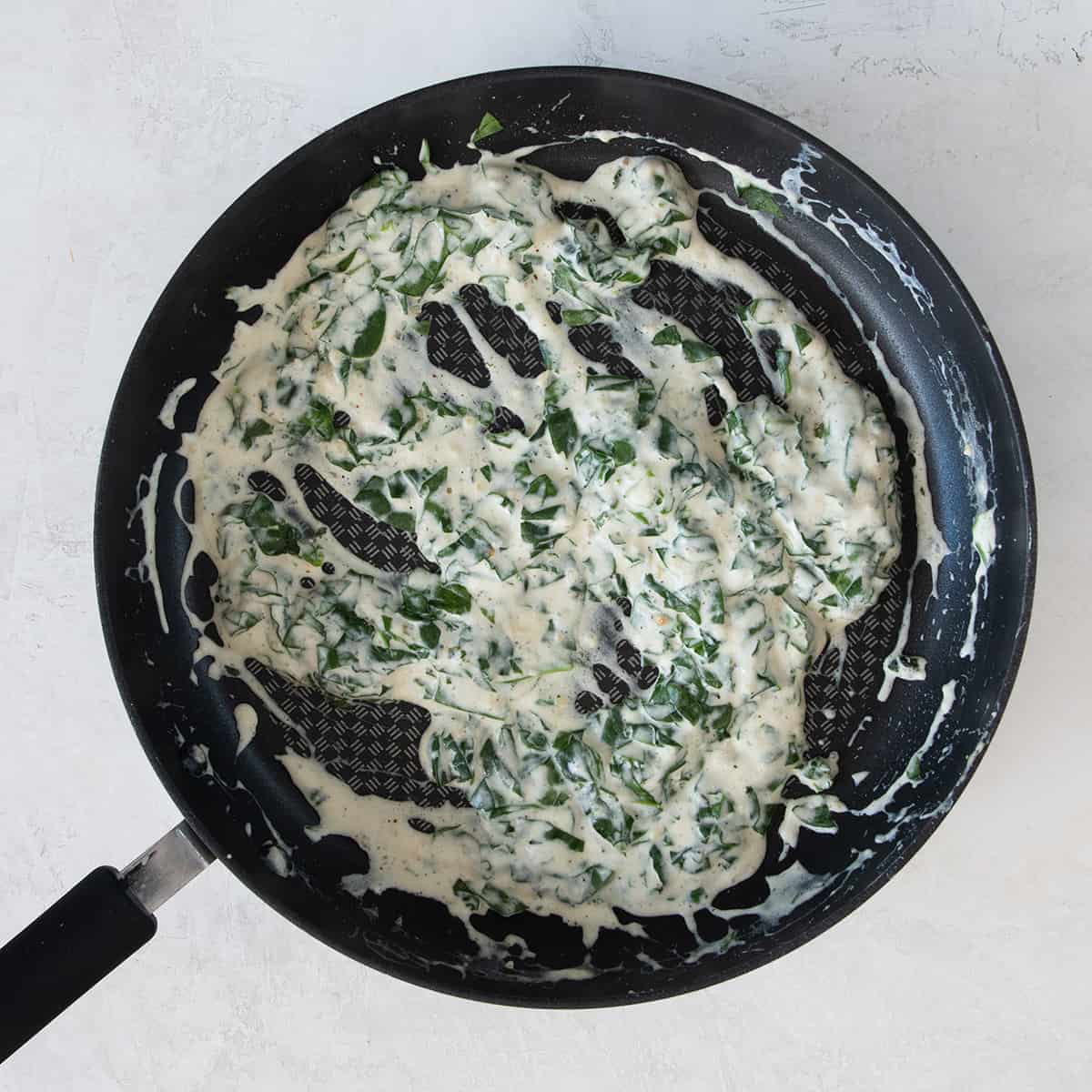 Spinach and cheese topping in a pan.