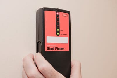 Placing a stud finder on the wall.
