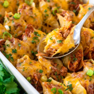 Taco stuffed shells in a large white pan with cilantro as garnish.