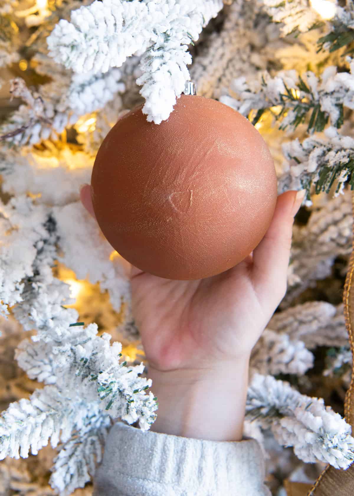 Closeup of a hand painted textured Christmas ornament in terracotta orange.