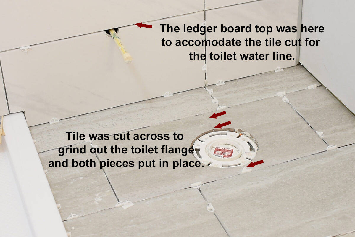 A tiled bathroom with arrows point to a cross tile cut for the toilet flange and the area to put up a ledger board.