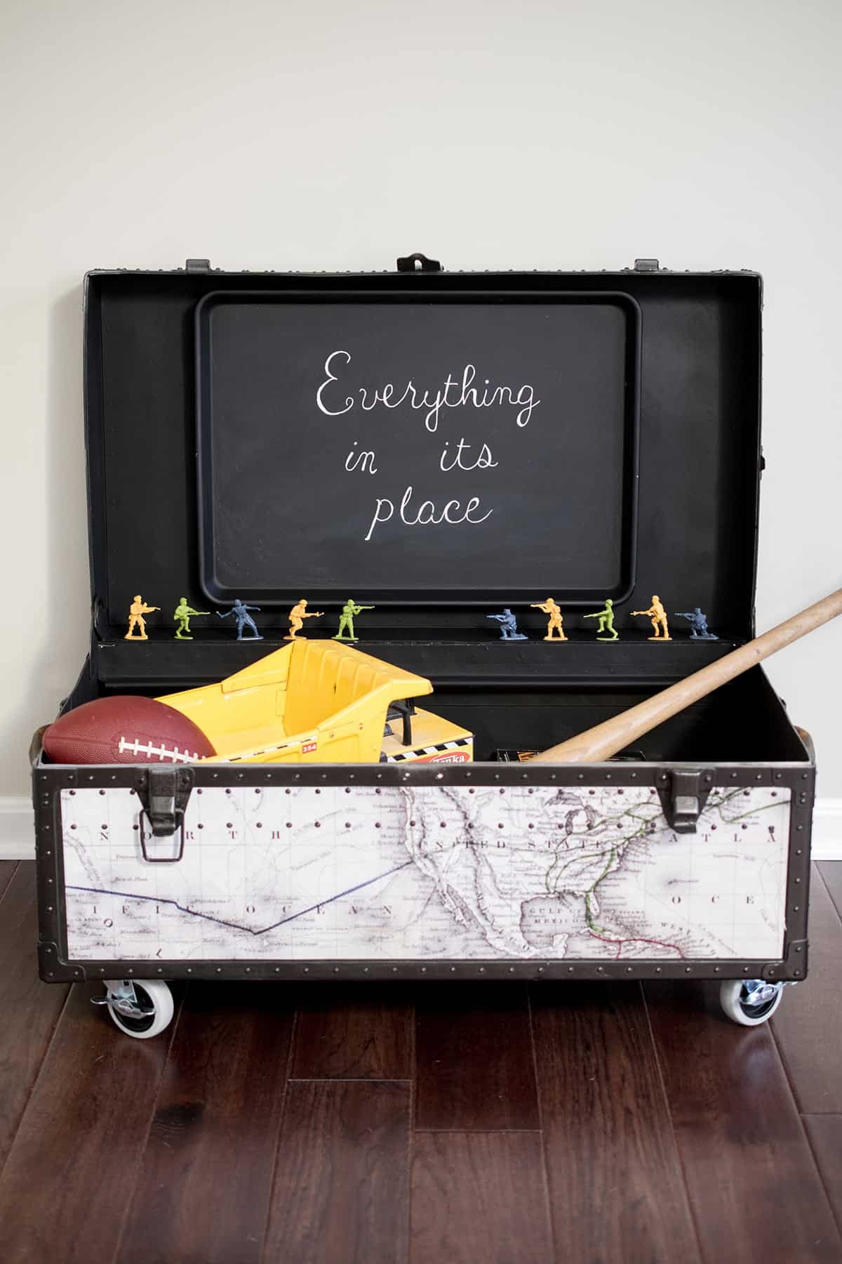 Steamer trunk makeover with magnetic chalkboard cookie sheet inside and storing sporting equipment and small toys.