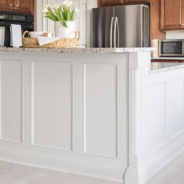 Large grey kitchen island with breakfast bar in traditional trim and two tone different color from the cabinets.