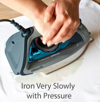 Hands pressing on iron to transfer an image using photo transfer paper.