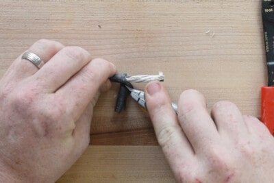 Hands trimming the casing around wires with a razor knife.