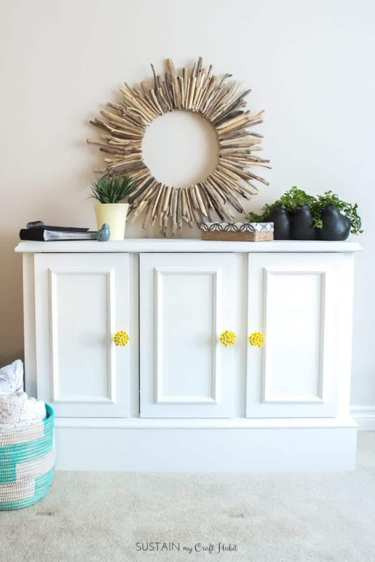White painted buffet with yellow painted knobs in a dining room.