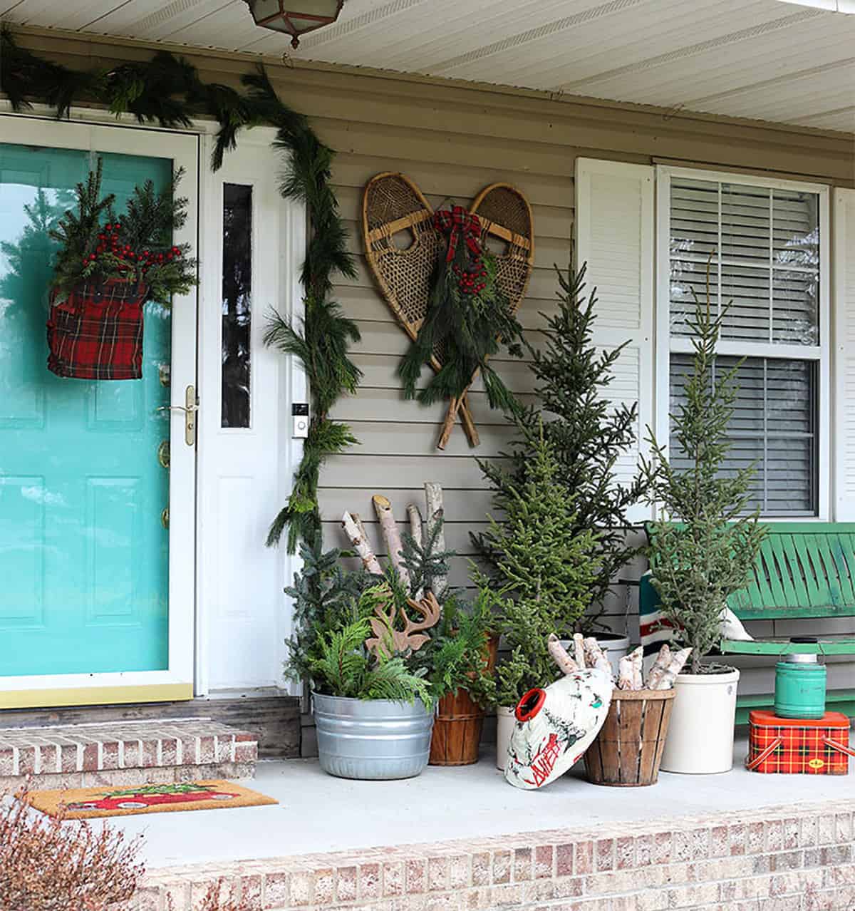 Vintage winter lodge with porch Christmas trees in small buckets.