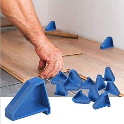 Man putting vinyl flooring spacers next to the wall.