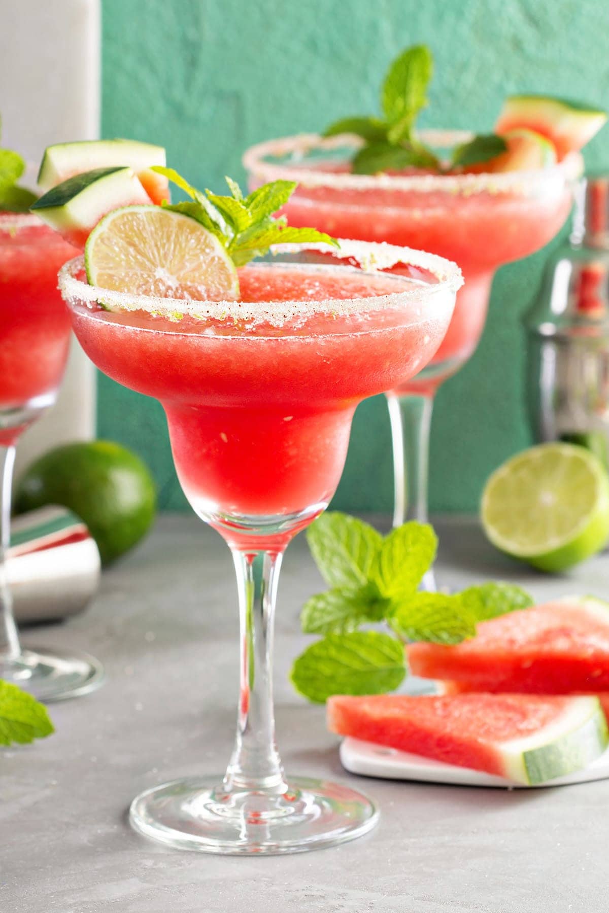 Closeup of Frozen Margarita with lime and watermelon garnish and sugared rim.