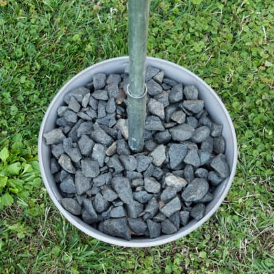 Plant container with gravel and metal pole inserted.