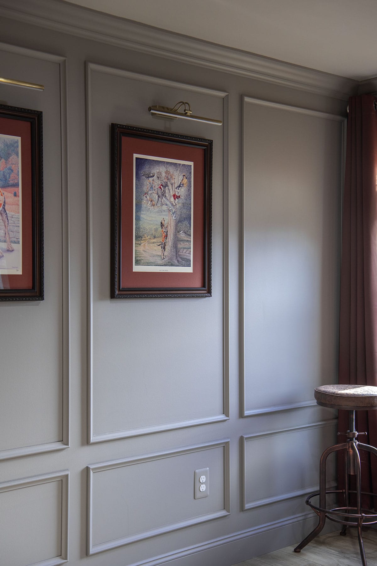 Photo of finished section of color drenched basement walls with box trim and framed custom art hung.